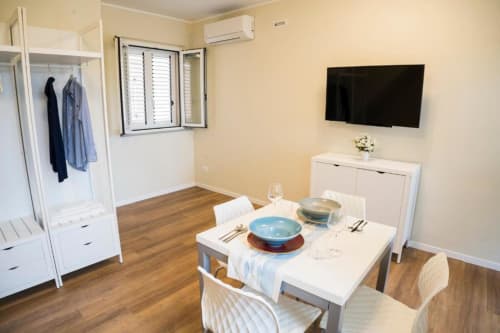 Moderna suite presso Residence Balconi del Conero con tavolo da pranzo, angolo cottura, TV, armadio e pavimenti in legno a Marcelli