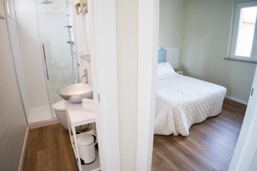 Modern apartment bedroom with en-suite bathroom at Residence Balconi del Conero, Marcelli, featuring wood flooring and sea