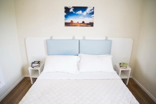 Modern bedroom with white bed, blue pillows, nightstands, and desert landscape art at Residence Balconi del Conero, Marcelli