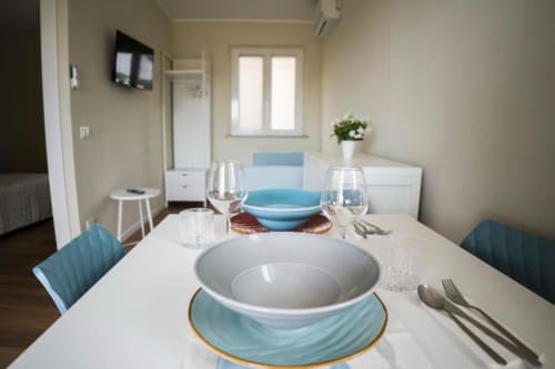 Elegant dining table setup in Residence Balconi del Conero apartment with blue accents, place settings, and sea view windows