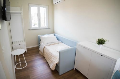 Bright modern bedroom with blue bed, white storage, wooden floors, window with sea view at Residence Balconi del Conero,