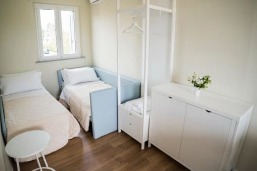 Bright modern apartment bedroom with two single beds, white furniture, wooden floors, and window at Residence Balconi del