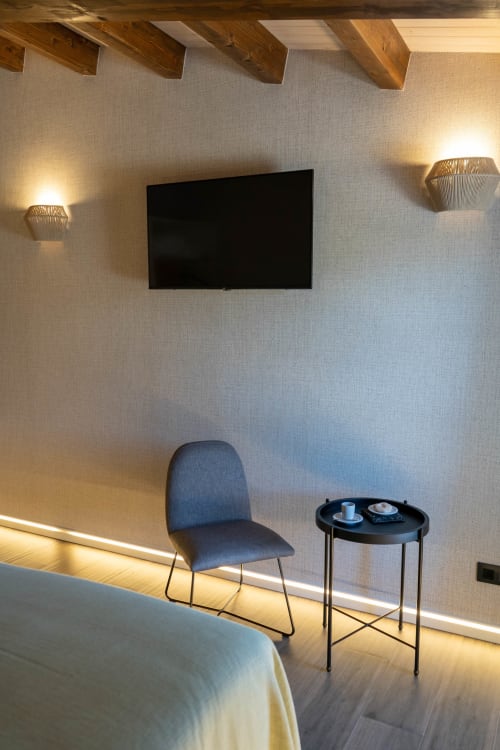 Habitación moderna en Casa Rural San Andres de Teixido con televisor de pared, sillón azul e iluminación ambiental