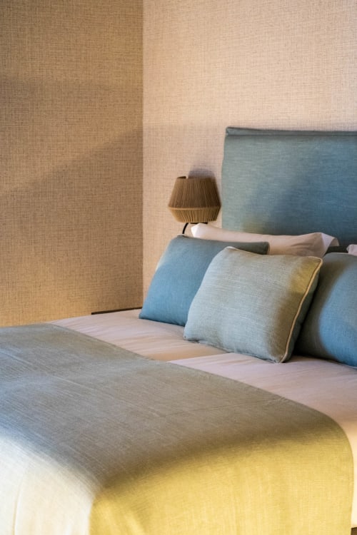 Dormitorio moderno en Casa Rural San Andres de Teixido con cabecero azul, almohadas decorativas, lámpara de mesa y textura beige