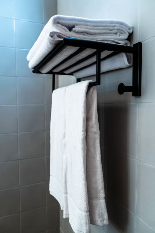 Toallero negro con toallas grises y blancas dobladas en el dormitorio de Casa Rural San Andrés de Teixido, Teixido, A Coruña