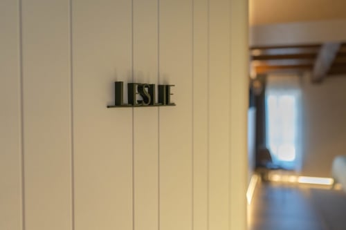 Placa con nombre Leslie en pared de paneles blancos en Casa Rural San Andrés de Teixido, Galicia