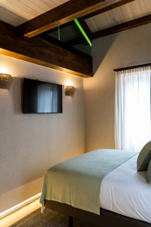 Dormitorio moderno en Casa Rural San Andrés de Teixido con cama, TV de pared, vigas de madera y vistas al mar