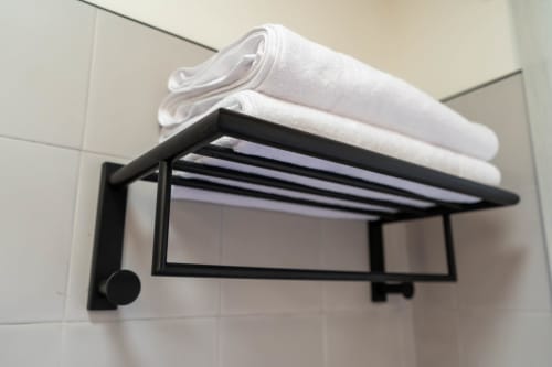 Toallero negro con toallas blancas enrolladas en el baño de Casa Rural San Andrés