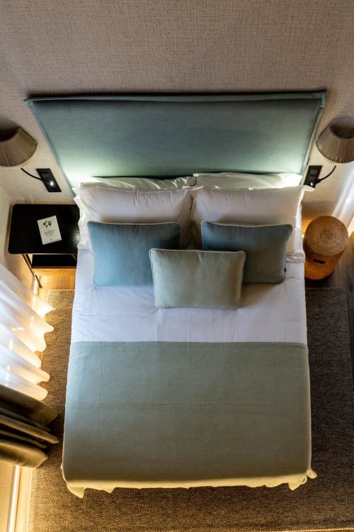 Vista aérea de dormitorio moderno en Casa Rural San Andrés de Teixido con cabecero turquesa, ropa de cama blanca y cojines decorativos