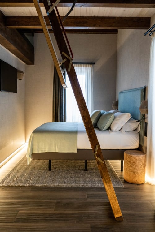 Dormitorio moderno en Casa Rural San Andrés de Teixido con vigas de madera, cama con cabecero azul y ventana con vistas al mar