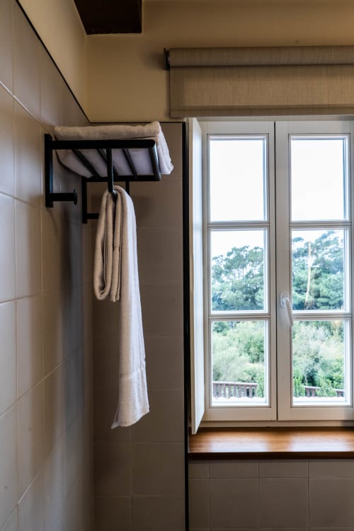 Baño moderno en Casa Rural San Andres de Teixido con toallero y amplias ventanas con vistas a la campiña gallega