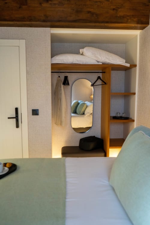 Dormitorio moderno en Casa Rural San Andres de Teixido con cama alta, espejo, estantería de madera y diseño costero en Teixido,