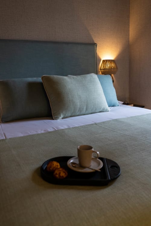 Habitación moderna en Casa Rural San Andres de Teixido con cama, almohadas, lámpara de noche y bandeja de bienvenida con café y pasteles