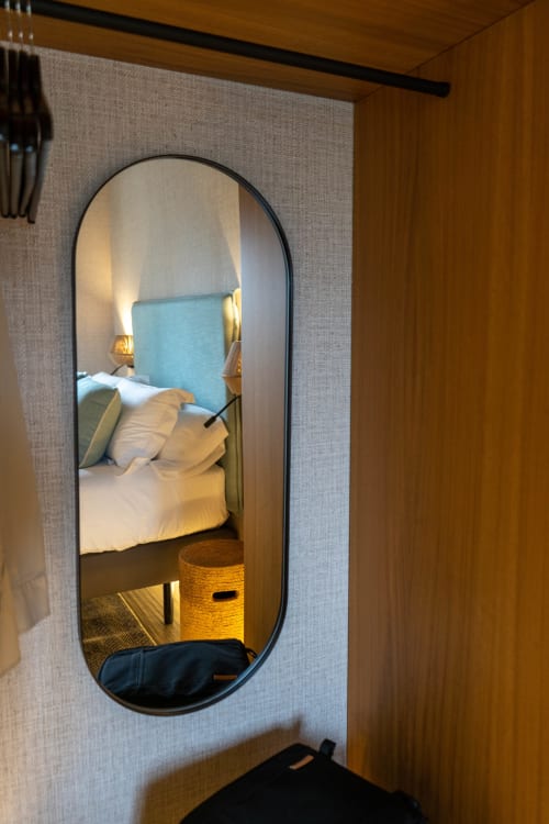 Acogedora habitación en Casa Rural San Andrés de Teixido con ropa de cama blanca, cabecero azul y espejo redondo en Galicia, España