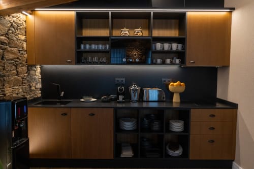 Moderna cocina con encimera negra, muebles de madera, estantes abiertos con vajilla y electrodomésticos de acero inoxidable en Casa