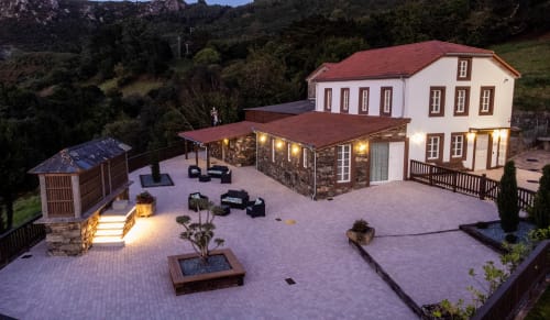 Vista crepuscular de la Casa Rural San Andrés de Teixido con patio iluminado, zona de descanso y montañas en Teixido, A