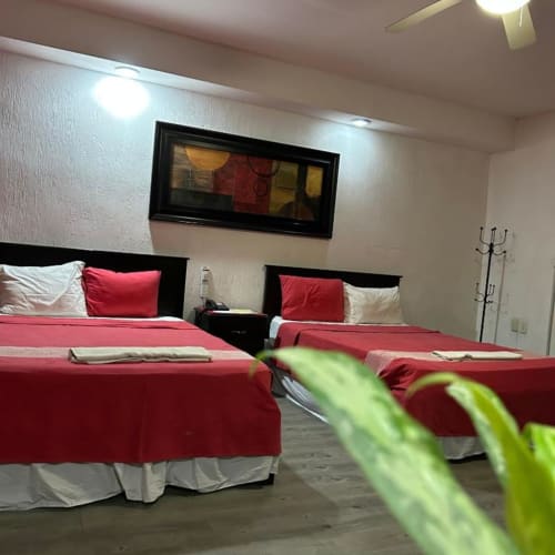Habitación del Hotel Makarios en Tuxtla Gutiérrez con dos camas queen de sábanas rojas y amenidades modernas