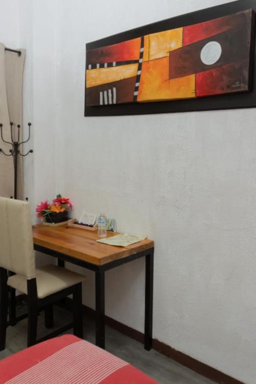 Escritorio moderno en habitación del Hotel Makarios con obra de arte abstracto colorida, mesa de madera y mobiliario contemporáneo en Tuxtla