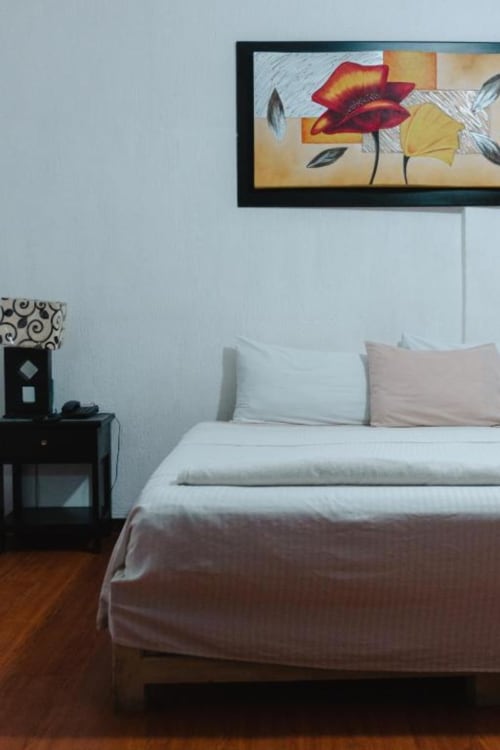 Habitación moderna del Hotel Makarios en Tuxtla Gutiérrez con cama, mesilla de noche y arte floral rojo en la pared