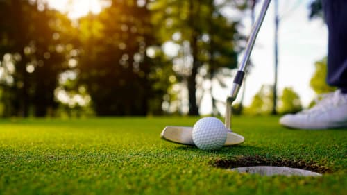 Golfer putting ball near hole at Brides-les-Bains resort with trees and green landscape