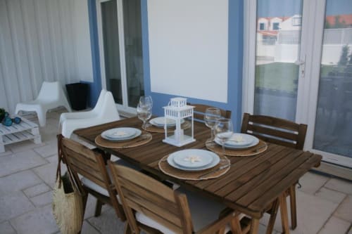Outdoor dining setup at Recantus Comporta with wooden table, place settings, and blue-trimmed terrace overlooking Portuguese