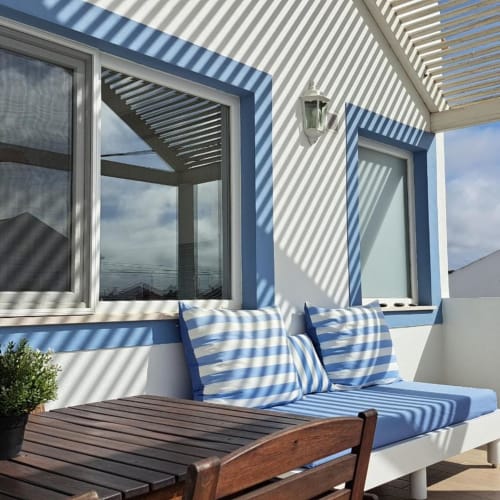 Blue and white striped cushions on a modern terrace at Recantus Comporta, Portugal, with coastal views and pergola shade
