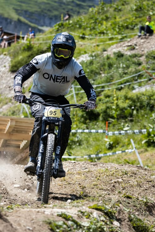Mountainbiker fährt Downhill in der grünen Berglandschaft bei Remiremont in Frankreich mit Zuschauern