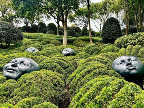 Surreal sculptural garden with oversized face heads nestled in manicured green hedges at Villa Eliane, Étretat