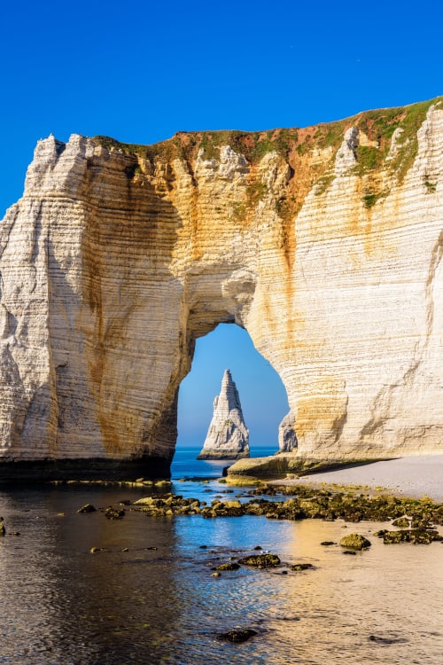 Dramatic white chalk cliffs with natural stone arch at Étretat beach, France
