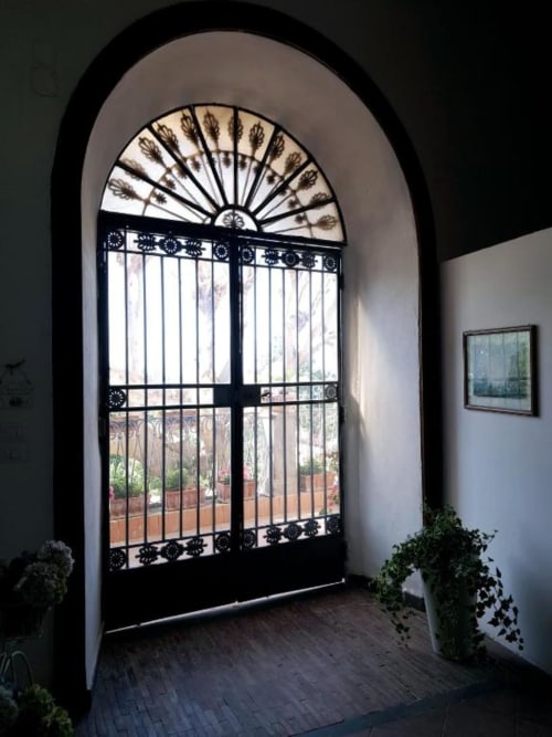 Elegante ingresso con arco decorativo e cancellata in ferro battuto nero dell'Hotel La Suite del Giardino, Napoli