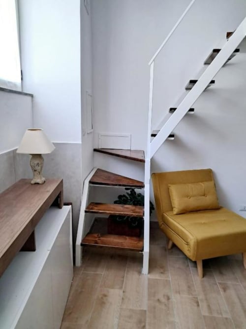 Elegante pianerottolo con poltrona gialla, scrivania in legno e lampada a La Suite del Giardino, Napoli