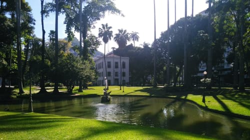 Lush green lawn and pond at Rio Vibes Hostel in Rio de Janeiro, with colonial white building and palm trees