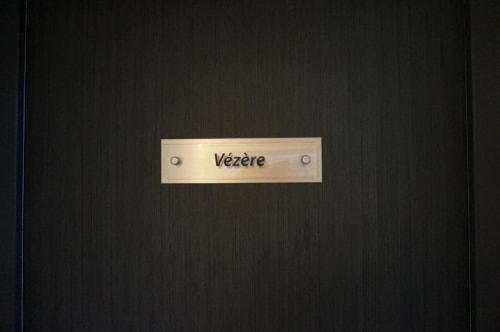 Plaque de chambre crème « Vézère » sur porte en bois foncé à l'Hôtel Saint Roch, Saint-Ybard