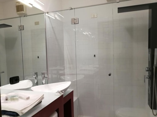 Modern bathroom with double sinks and frameless glass shower enclosure at Carducci Apartment, THE V Collection, Turate