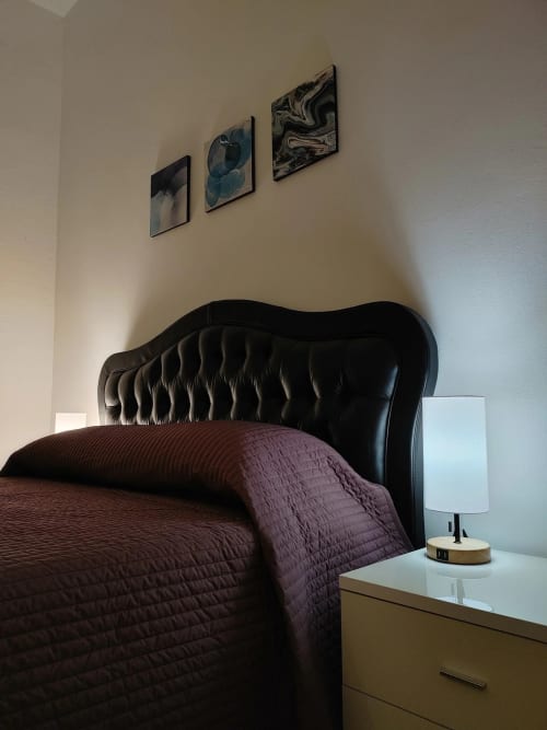 Modern bedroom at THE V Collection Milano with black tufted headboard, burgundy bedding, and abstract wall art