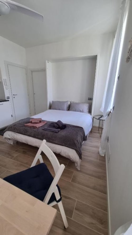 Camera moderna presso Maso Kreuzberg a Trento con letto, poltrona bianca e vista sul giardino