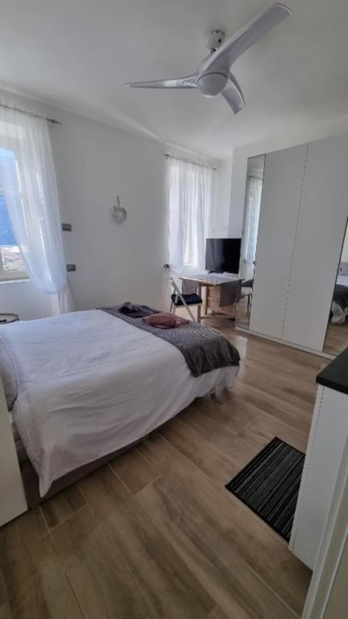 Camera moderna del Maso Kreuzberg con letto bianco, ventilatore a soffitto, pavimenti in legno e vista sul giardino