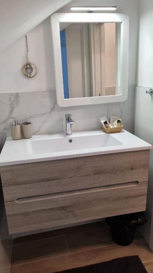 Vanità moderna del bagno con lavabo bianco, cassetti in legno e specchio illuminato nell'appartamento Maso Kreuzberg a Trento