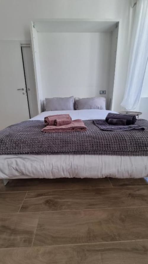 Camera da letto moderna con alcova letto integrata, biancheria grigia trapuntata e asciugamani arrotolati al Maso Kreuzberg, Trento