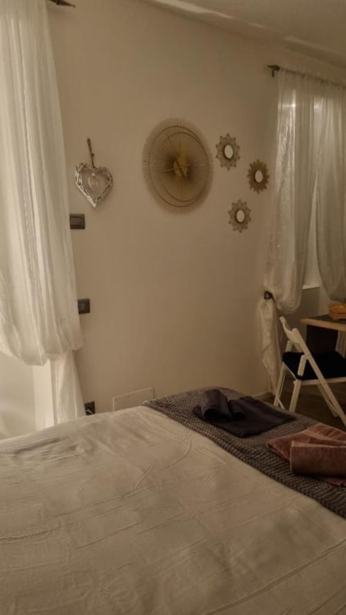Camera da letto luminosa dell'appartamento Maso Kreuzberg a Trento con tende bianche, arte decorativa e vista sul giardino