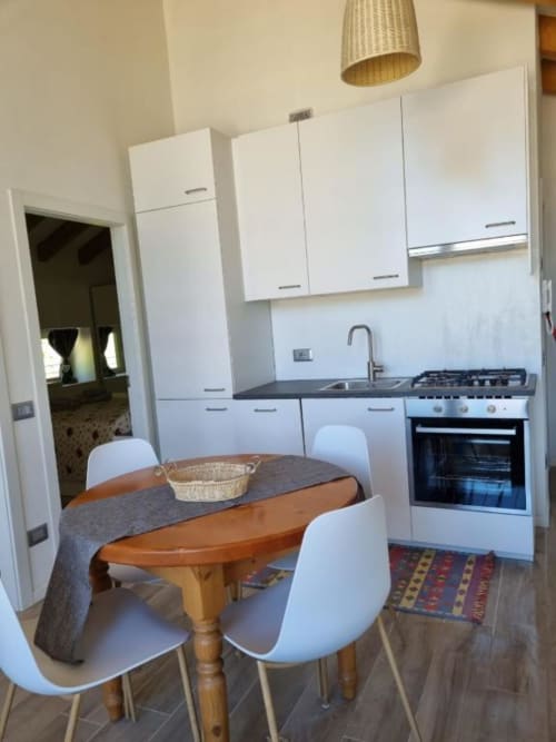 Cucina e zona pranzo moderna dell'appartamento Maso Kreuzberg a Trento con tavolo in legno, sedie bianche e acciaio inox