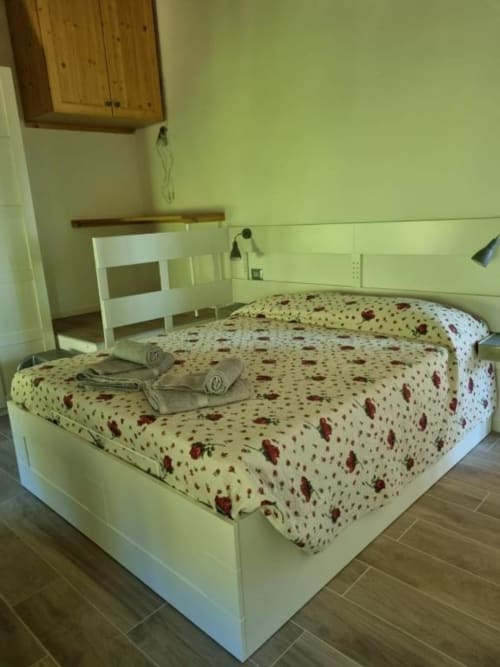Camera accogliente al B&B Maso Kreuzberg a Trento con biancheria floreale, arredi in legno e vista sulle montagne