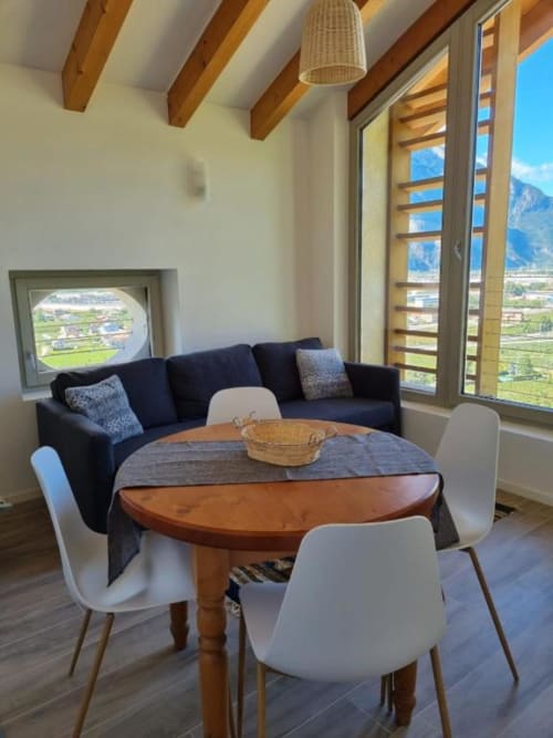Moderno appartamento a Maso Kreuzberg con vista montagna, tavolo rotondo in legno, sedie bianche, divano scuro e