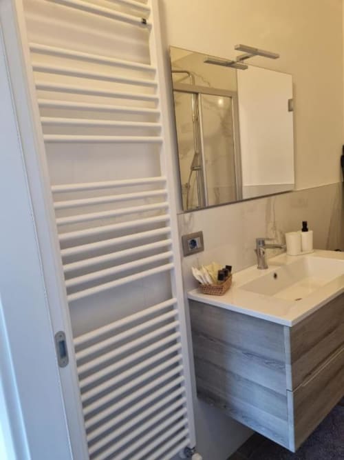 Bagno moderno a Maso Kreuzberg con radiatore bianco, mobile lavabo e specchio nell'appartamento di Trento