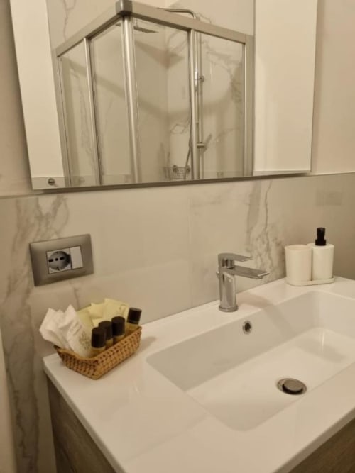 Moderno bagno dell'appartamento Maso Kreuzberg a Trento con piastrelle in marmo, box doccia in vetro e lavabo bianco