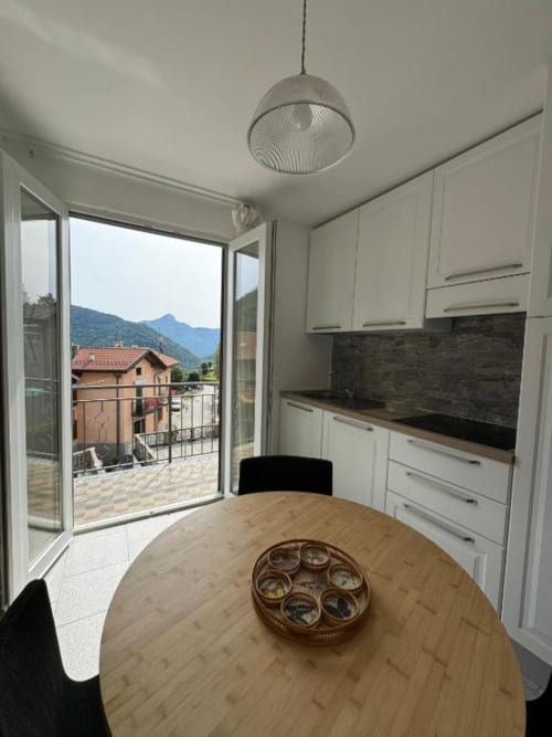 Cucina moderna con zona pranzo, vista montagna e balcone nell'appartamento Sormano di THE V Collection