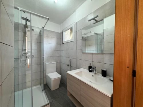 Moderno bagno nell'appartamento di Sormano con doccia in vetro, wc e lavabo con specchio