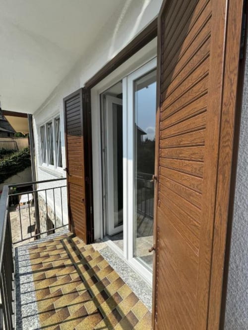 Balcone moderno con persiane in legno e porte in vetro affacciate sulle montagne di Sormano