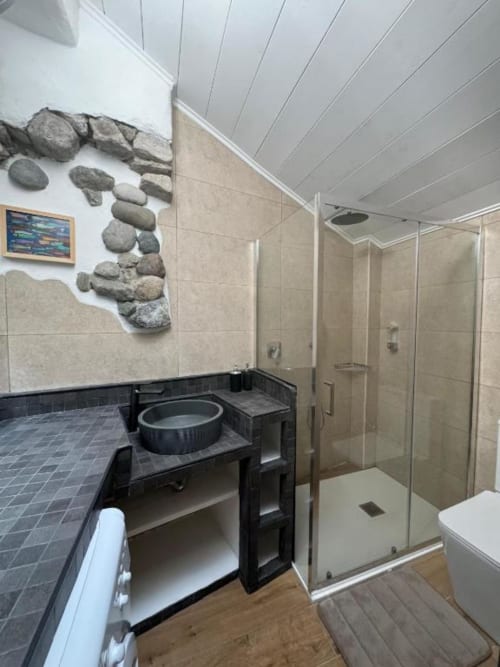 Bagno moderno nell'appartamento di Sormano con doccia walk-in, vanità nera e parete decorativa in pietra
