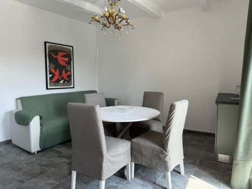 Appartamento Sormano 1: zona living e pranzo con tavolo rotondo, sedie imbottite, divano verde e elegante lampadario